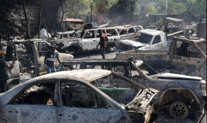 People look for salvageable pieces from burned cars at a shop that was set on fire by armed gangs in Port-au-Prince on 25 March. Photograph: Odelyn Joseph/AP